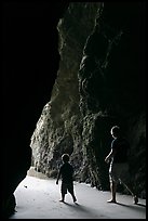 Father and son walking towards the light in sea cave. Bandon, Oregon, USA (color)