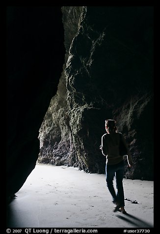 Woman walking out of sea cave. Bandon, Oregon, USA (color)