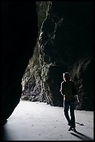 Woman walking out of sea cave. Bandon, Oregon, USA
