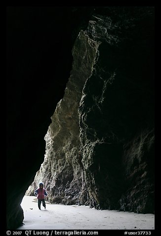 Infant walking into sea cave. Bandon, Oregon, USA (color)