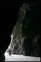 Infant walking into sea cave. Bandon, Oregon, USA