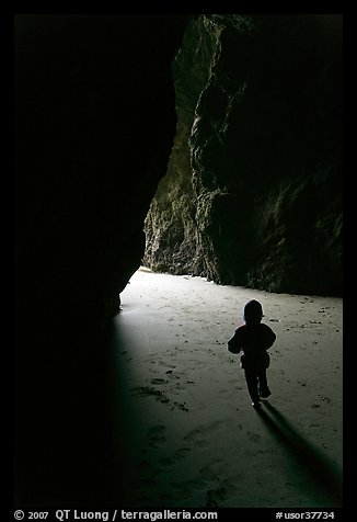 Infant walking towards the light in sea cave. Bandon, Oregon, USA