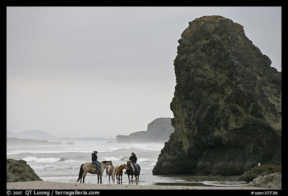 Women ridding horses next to sea stack. Bandon, Oregon, USA