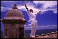 Man standing next to a lookout turret, with arms spread, El Morro Fortress. San Juan, Puerto Rico