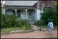 Woman walking dog in front of a crooked house. Selma, Alabama, USA