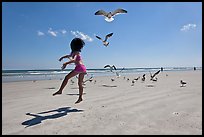 Girl jumping on beach with seagulls flying, Jetty Park. Cape Canaveral, Florida, USA