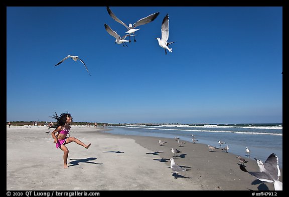 Beach with flying seagulls and girl, Jetty Park. Cape Canaveral, Florida, USA