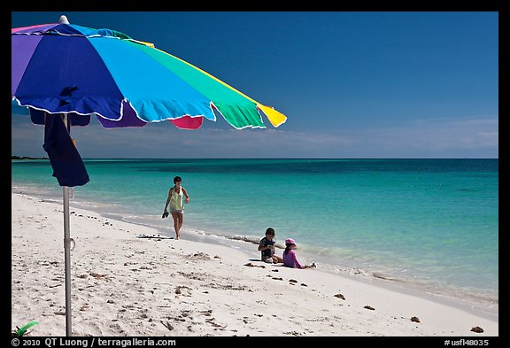 Beach with unbrella, children playing and woman strolling,. The Keys, Florida, USA (color)