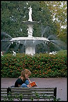 Woman sitting on bench with book in front of Forsyth Park Fountain. Savannah, Georgia, USA