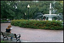 Forsyth Park Fountain with woman sitting on bench with book. Savannah, Georgia, USA