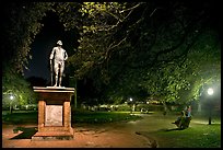 Park with statue and couples sitting on public benches at night. Charleston, South Carolina, USA (color)