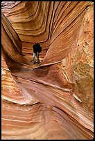 Hiker with backpack on a side formation of the Wave. Coyote Buttes, Vermilion cliffs National Monument, Arizona, USA (color)