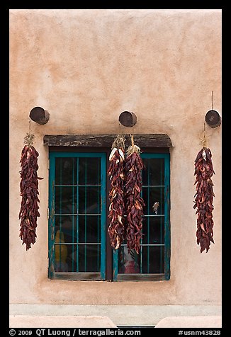 Ristras hanging from vigas and blue window. Taos, New Mexico, USA