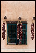 Ristras hanging from vigas and blue window. Taos, New Mexico, USA