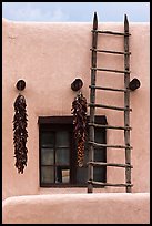 Strings of red peppers and ladder on building in pueblo style. Taos, New Mexico, USA