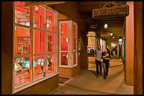 Couple walking by night in front of gallery. Santa Fe, New Mexico, USA (color)