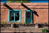 Adobe facade with flowers, windows, and vigas shadows. Santa Fe, New Mexico, USA (color)