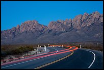 Road with light trails and Organ Mountains at dusk. Organ Mountains Desert Peaks National Monument, New Mexico, USA ( color)