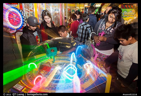 Family plays arcade game with spining lights. Reno, Nevada, USA (color)