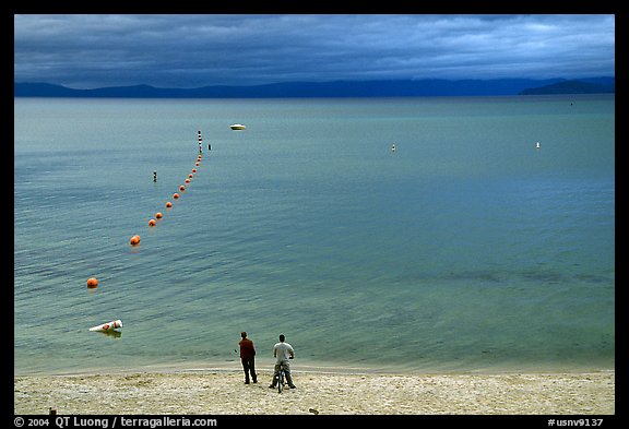 Men standing on beach under dark sky, South Lake Tahoe, California. USA