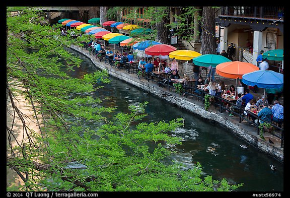 Tables under colorful umbrellas next to canal. San Antonio, Texas, USA (color)