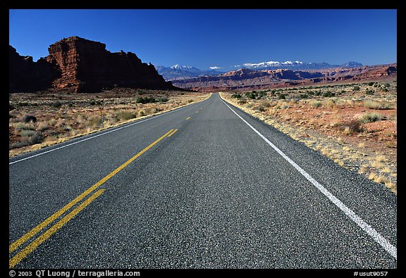 Road, sandstone cliffs, snowy mountains. Utah, USA