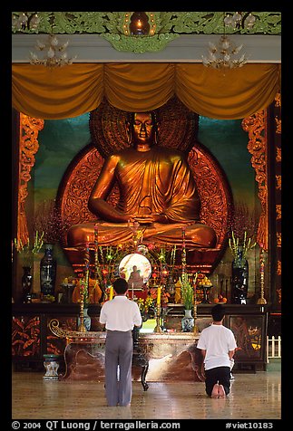 Men worshipping in front of a large Buddha state, Xa Loi pagoda. Ho Chi Minh City, Vietnam