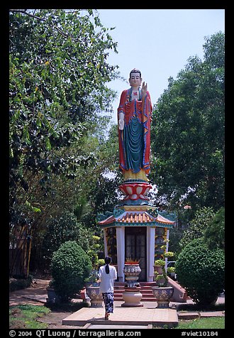 Woman praying under a large buddhist statue. Ho Chi Minh City, Vietnam