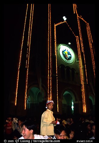 Child with christmas hat in front of St Joseph Cathedral on Christmas eve. Ho Chi Minh City, Vietnam