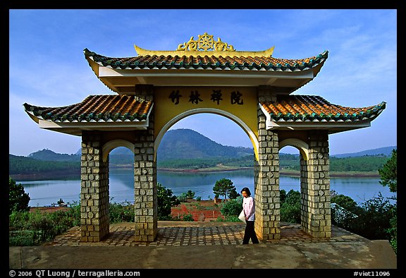 Pagoda gate with woman standing near lake. Da Lat, Vietnam