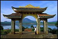 Pagoda gate with woman standing near lake. Da Lat, Vietnam