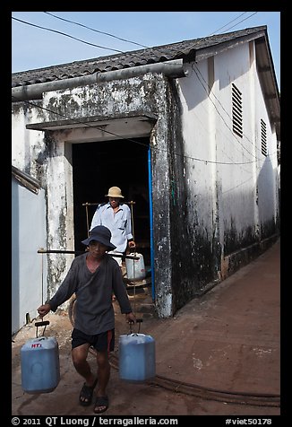 Workers carrying out containers of nuoc mam, Duong Dong. Phu Quoc Island, Vietnam (color)