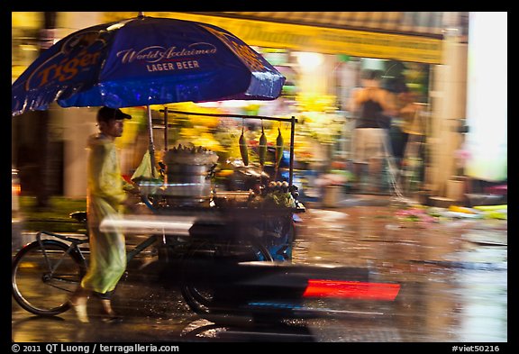 Man riding riding food cart in the rain. Ho Chi Minh City, Vietnam