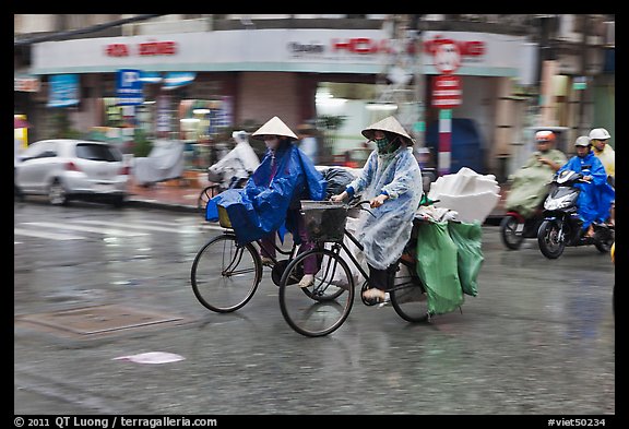 Women riding bicyles in the rain. Ho Chi Minh City, Vietnam (color)