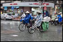 Women riding bicyles in the rain. Ho Chi Minh City, Vietnam