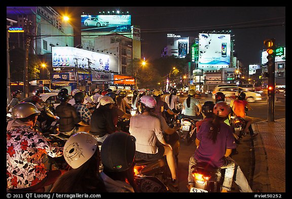 Motorbikes waiting at traffic light at night. Ho Chi Minh City, Vietnam