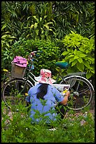 Woman reading newspaper next to bicycle in park. Ho Chi Minh City, Vietnam (color)