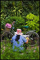 Woman reading newspaper next to bicycle in park. Ho Chi Minh City, Vietnam