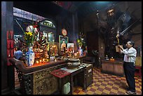 Man in prayer, with fierce statue of general behind, Jade Emperor Pagoda, district 3. Ho Chi Minh City, Vietnam ( color)