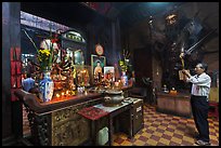 Man in prayer, with fierce statue of general behind, Jade Emperor Pagoda, district 3. Ho Chi Minh City, Vietnam ( color)