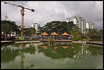 Reflecting pool, completed residential buildings, and crane, Phu My Hung, district 7. Ho Chi Minh City, Vietnam