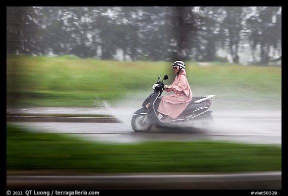 Scooter rider in the rain on parkway, district 7. Ho Chi Minh City, Vietnam (color)