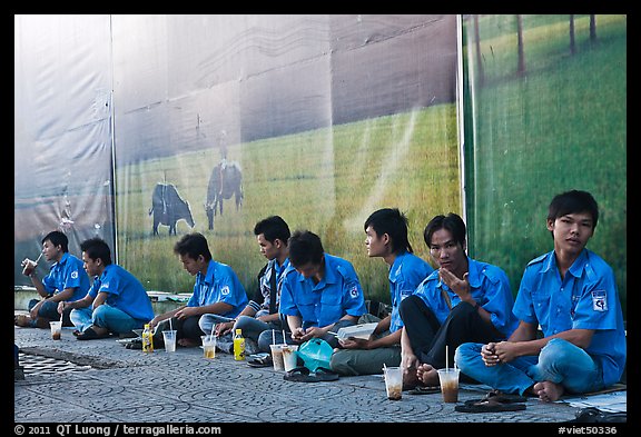 Uniformed students sitting in front of backdrops depicting traditional landscapes. Ho Chi Minh City, Vietnam (color)