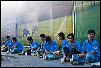 Uniformed students sitting in front of backdrops depicting traditional landscapes. Ho Chi Minh City, Vietnam ( color)