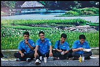 Uniformed students eating in front of backdrop depicting rural landscape. Ho Chi Minh City, Vietnam (color)