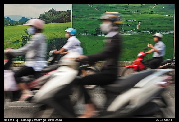 Motorbike riders speeding in front of backdrops depicting traditional landscapes. Ho Chi Minh City, Vietnam (color)