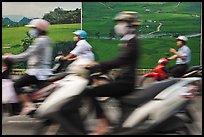 Motorbike riders speeding in front of backdrops depicting traditional landscapes. Ho Chi Minh City, Vietnam ( color)