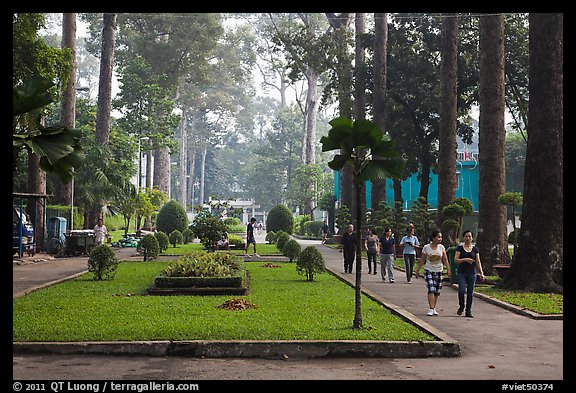 People strolling in alley below tall trees, Cong Vien Van Hoa Park. Ho Chi Minh City, Vietnam (color)