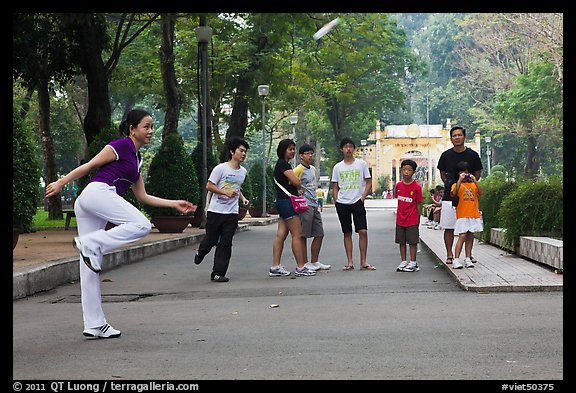 Young woman playing footbag as audience watches, Cong Vien Van Hoa Park. Ho Chi Minh City, Vietnam (color)