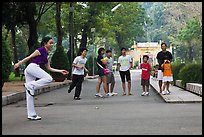 Young woman playing footbag as audience watches, Cong Vien Van Hoa Park. Ho Chi Minh City, Vietnam (color)